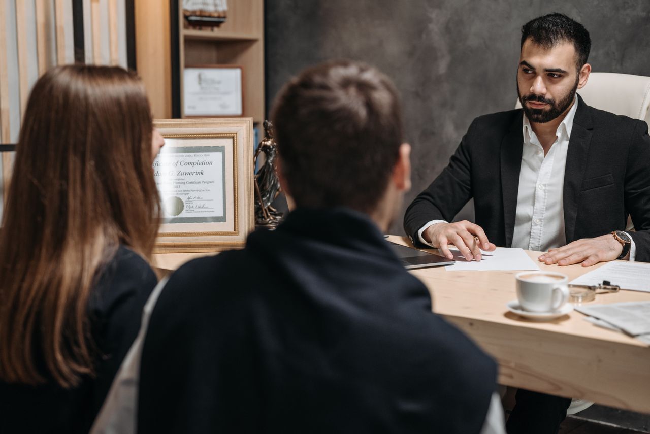 Home A lawyer in an elegant office meeting with clients, discussing documents.